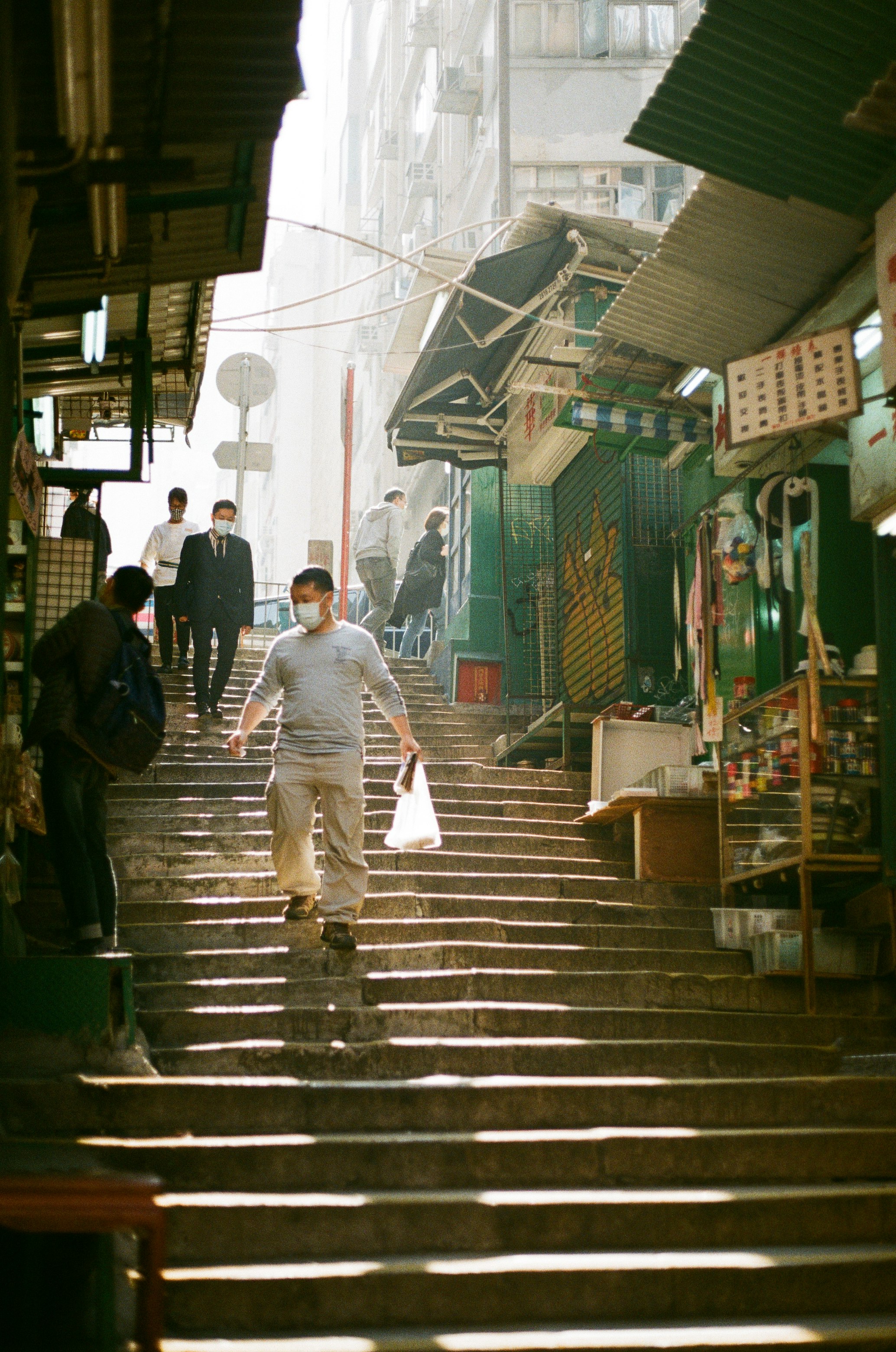 man in gray dress shirt walking on sidewalk during daytime